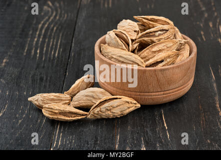 Wild uzbek inshell almonds in a bowl on wooden background Stock Photo