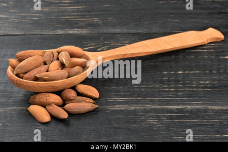 Uzbek almonds without shell in spoon on wooden background Stock Photo