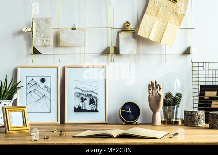 Notebook and posters on wooden desk in home office interior with gold clock Stock Photo