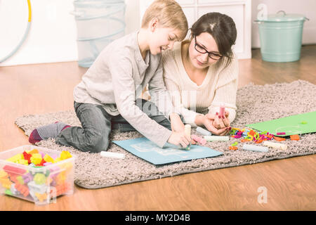 Single mother spending time with her son by drawing together on a fluffy carpet Stock Photo