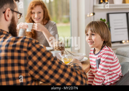 Smiling boy looking at his father while eating breakfast in the morning Stock Photo