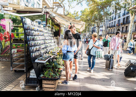 Barcelona, Spain - September 20, 2017: Tourists taking their luggage along Les Rambles while a young couple chooses a gift in Barcelona, Catalonia, Sp Stock Photo