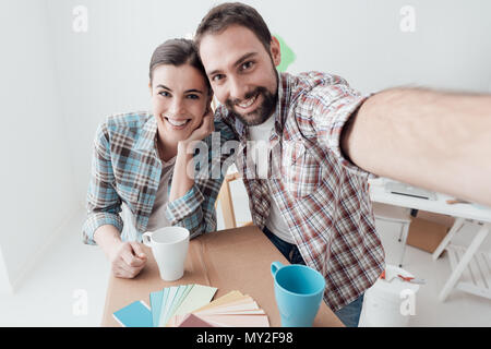 Smiling young couple moving into their new house and doing a home makeover, they are taking a selfie Stock Photo