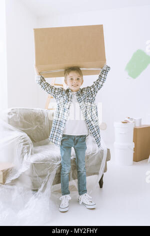 Smiling boy carrying a huge box, home renovation and relocation concept Stock Photo