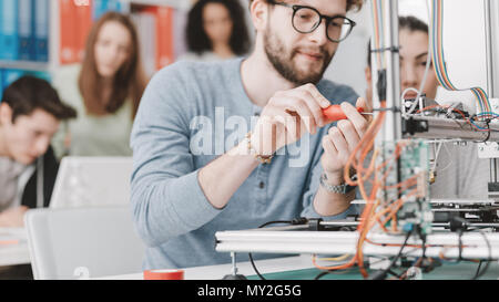 Engineering students using a 3D printer in the laboratory, a student is using a screwdriver Stock Photo