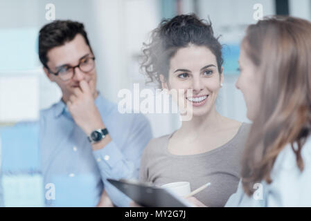 Young business people working together in the office and discussing new ideas, a woman is smiling, start up and enterprise concept Stock Photo