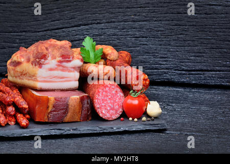 Different types of sausages with spices on slate on old wood background close up Stock Photo