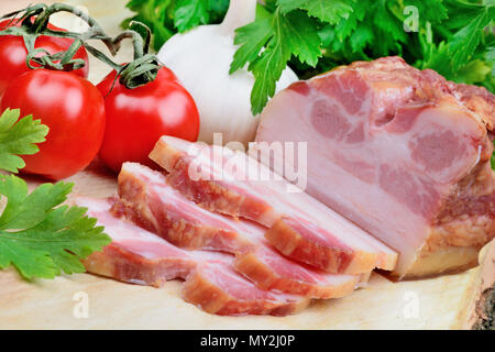 Sliced of bacon with cherry tomatoes and garlic on wood table Stock Photo