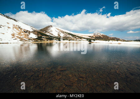 Frozen mountain lake with blue ice Stock Photo