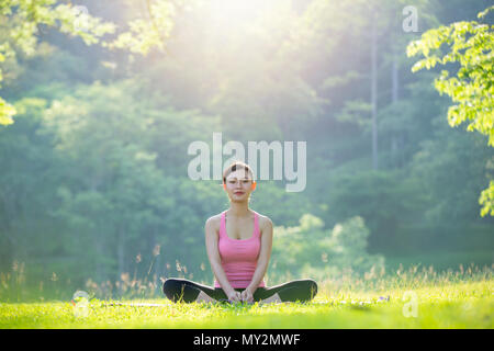 Beautiful pregnant woman relaxing in the park,   Yoga lady practicing in park outdoor, Meditation, Exercise. Stock Photo