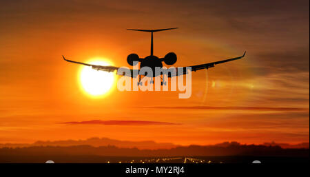 Airplane silhouette landing at the airport during sunset. Sun, shape of private jet plane and flashing runway lights. Stock Photo