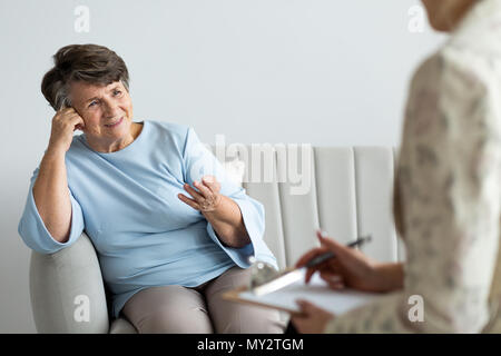 Smiling satisfied senior woman talking to a psychotherapist Stock Photo