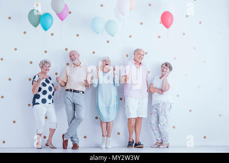 Happy senior people with colorful balloons celebrating friend's birthday