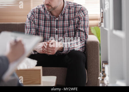 Close-up of a man sitting on a couch during marital consultation in an office Stock Photo