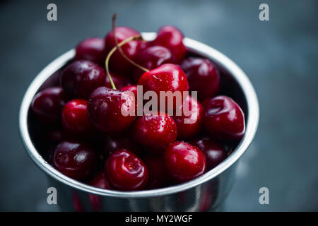 Cherries with a small metal bucket on a grey concrete background, summer berries concept with copy space. Neutral color tones still life Stock Photo