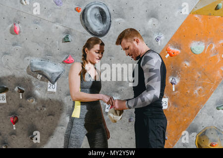 Half-length shot of young man and woman in sportive attire applying talcum powder to their hands from a bag Stock Photo