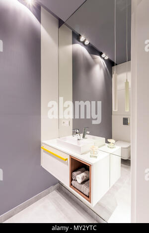 Mirror and white washbasin cabinet in grey bathroom interior with light Stock Photo