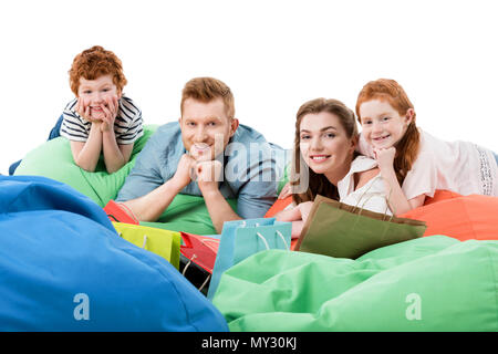 happy family with two children resting on bean bag chairs and smiling at camera after shopping Stock Photo