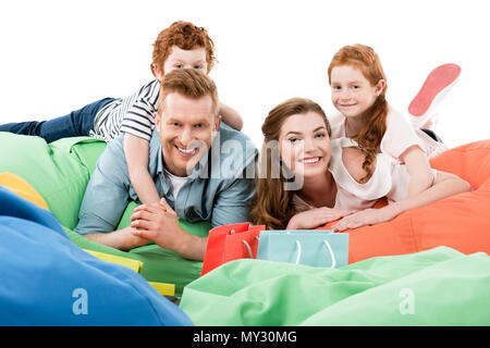 happy family with two kids lying on bean bag chairs and smiling at camera after shopping Stock Photo