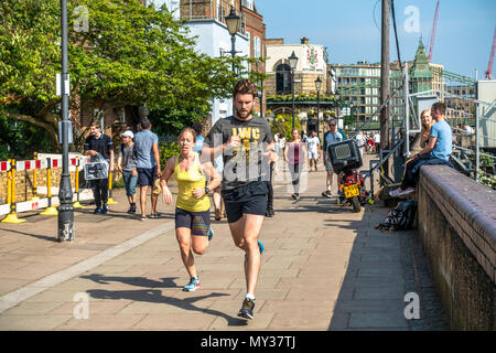 A man and woman run along The Lower Mall, a path running alongside The River Thames at Hammersmith in London, UK. Stock Photo