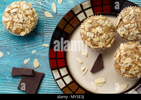 Tasty sugar muffins with almond, walnuts and chocolate on blue wooden background Stock Photo