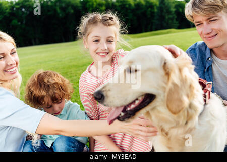 happy family with two children stroking dog at park Stock Photo
