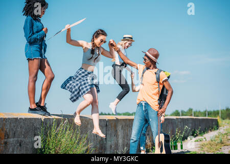multiethnic group of young friends jumping of parapet together Stock Photo