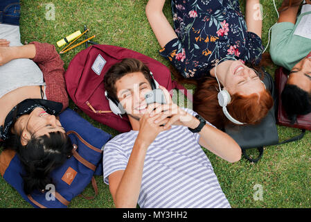 Group of college students relaxing together on grass between classes Stock Photo