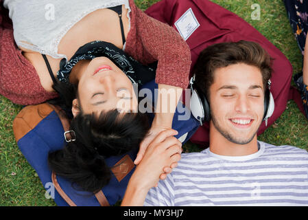 Young couple relaxing on grass together, overhead view Stock Photo