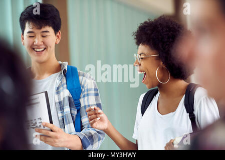 Students laughing together in corridor Stock Photo