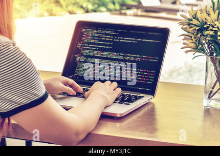 Close-up of programmer's hands working on source codes over a laptop on a summer day. Stock Photo