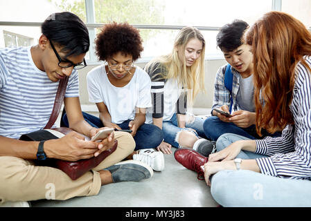 Students sitting together using smart phones Stock Photo