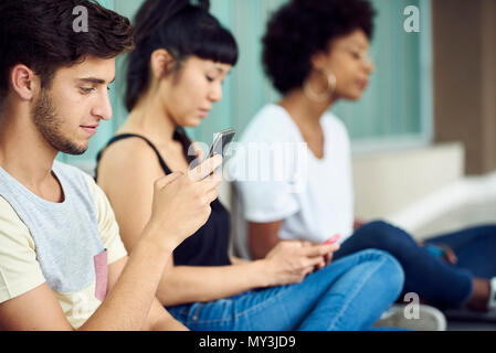 Students killing time with smartphones between classes Stock Photo