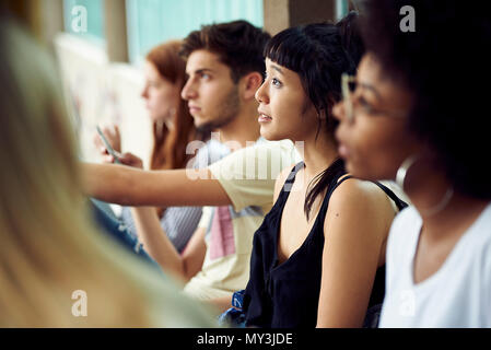 Students sitting in a row, looking up attentively Stock Photo