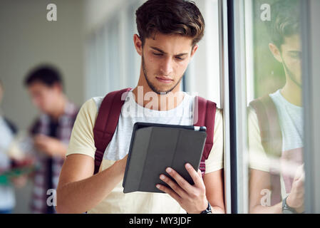 Male college student using digital tablet in corridor Stock Photo