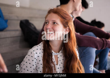 Young woman chatting with friend and smiling cheerfully] Stock Photo
