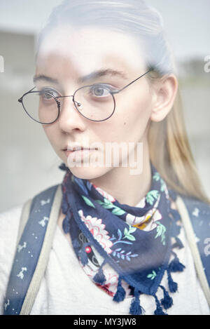 Young woman looking through window, portrait Stock Photo