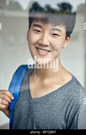 Young man smiling through window, portrait Stock Photo