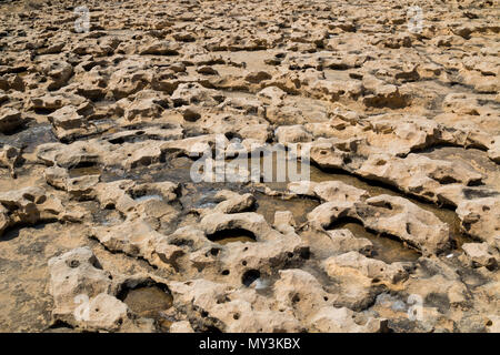 Textured rocks on the seaside of mediterranean island Gozo, Malta. Sea water in the holes of the rocks, which remind moon land. Stock Photo