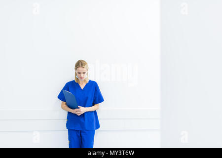 upset surgeon with diagnosis standing at wall in hospital corridor Stock Photo