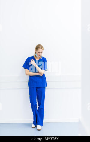 upset female surgeon standing at wall in hospital corridor Stock Photo