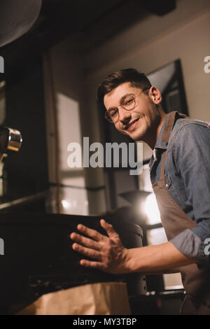 side view of smiling young coffee roaster working in coffee shop Stock Photo