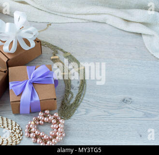 gift boxes with gifts. Women's jewelry on a light wooden background. Stock Photo