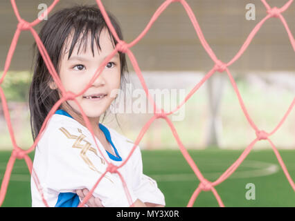Soccer kid girl is stand inside a soccer goal on soccer training field Stock Photo