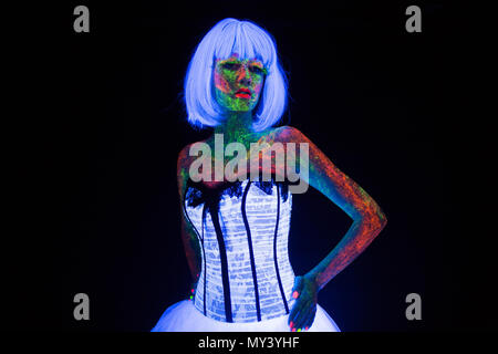 concept of wedding photosession in neon lighting in vogue style bride glows in the dark young girl in white wedding dress under the UV rays on a dark background in the studio Stock Photo