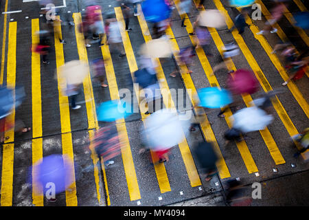 Motion blurred pedestrians crossing Hong Kong street in the rain Stock Photo