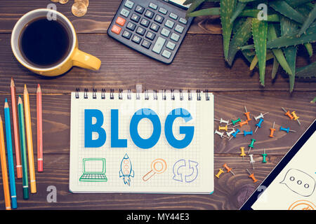 Tablet with web icon  blog  on a wooden table with office tools.The home page of the blogs, social technology , writing website. Stock Photo