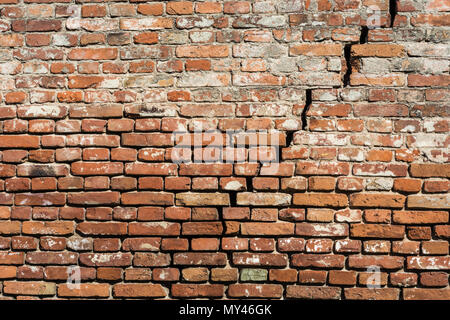 Empty very old red brick wall texture with cracks. Painted Distressed wall surface. Grunge red stonewall background. building facade damaged plaster Stock Photo
