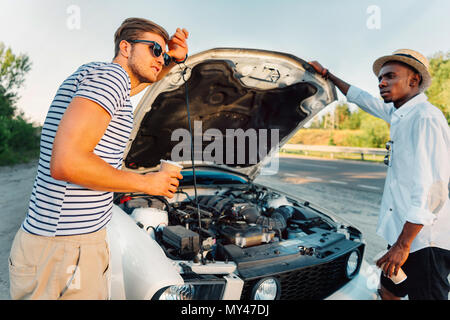 multiethnic friends with coffee to go having conversation near broken car Stock Photo
