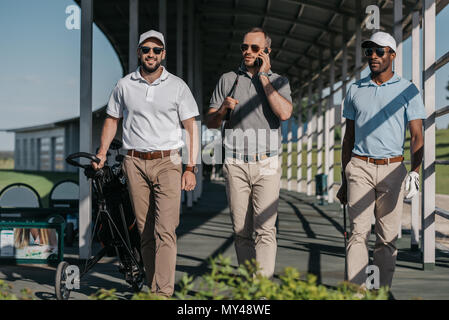 man talking on smartphone while friends walking near by Stock Photo